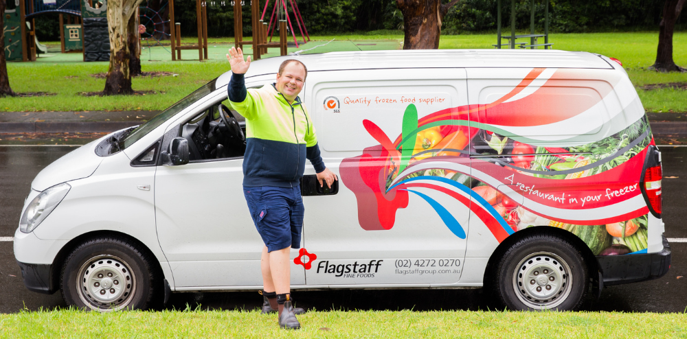 An image of a person waving to a client in front of a vehicle